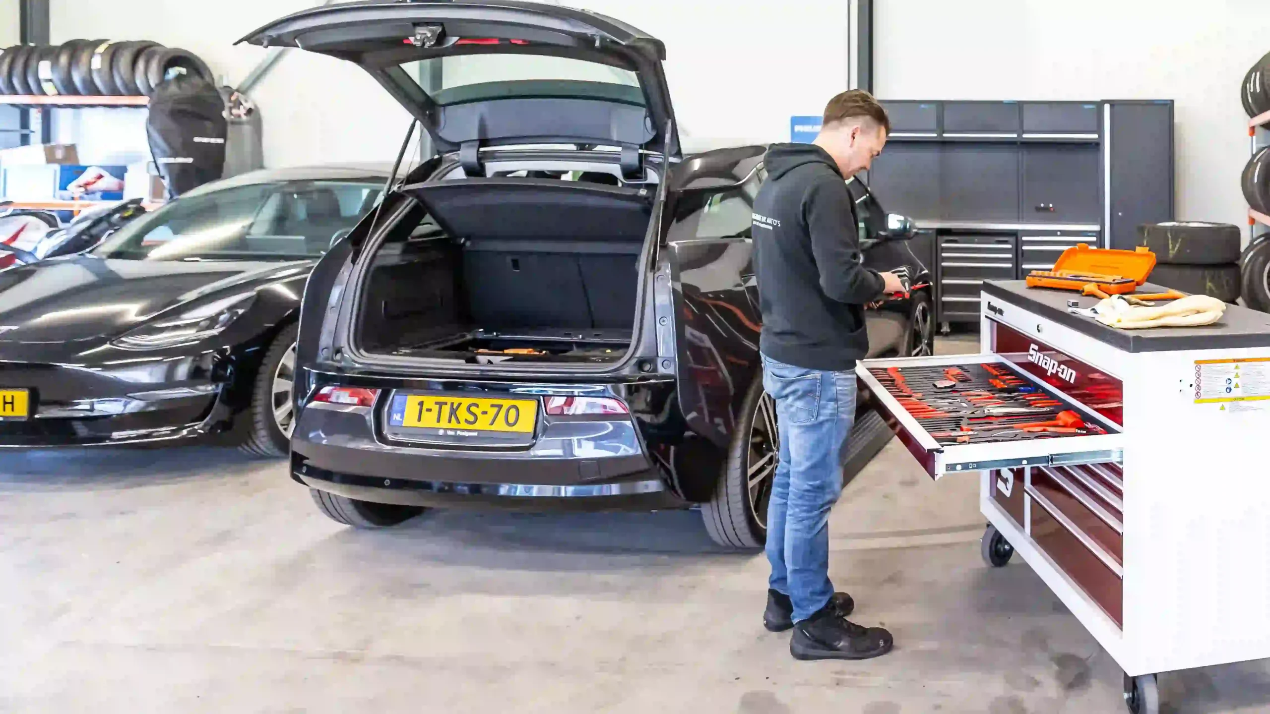 Man werkt aan auto met laptop.